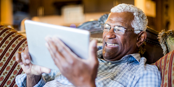 Senior man laying on couch and looking at tablet or ipad